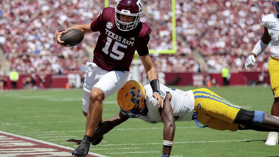 COLLEGE STATION, TEXAS - SEPTEMBER 07: Conner Weigman #15 of the Texas A&M Aggies scrambles past Micah Davey #48 of the McNeese State Cowboys in the second quarter at Kyle Field on September 07, 2024 in College Station, Texas.