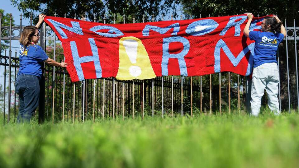 Kathy Danas and Melissa Yarborough hang a crochet sign that reads “No More Harm” as members of the group Houston Stitching Together meet to work on protest signs against Houston ISD, Sept. 8, 2024, in Houston.