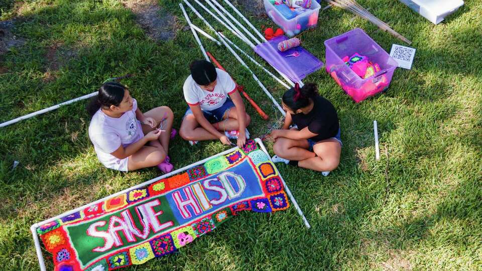 Sisters Alexa, Nicole and Kenya Torres work on attaching crochet patterns to PVC piping to display work as members of the group Houston Stitching Together meet to assemble on protest signs against Houston ISD, Sept. 8, 2024, in Houston.