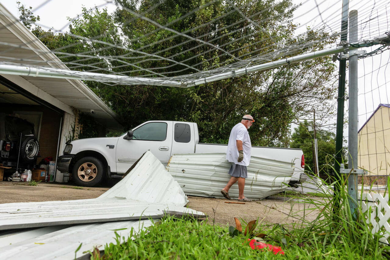 Rick Armstrong's removes metal roofing and fencing that flew from a restaurant about a block from his house and onto his truck in his driveway during Hurricane Francine on Thursday, Sept. 12, 2024 in Houma, La. (Chris Granger /The Times-Picayune/The New Orleans Advocate via AP)