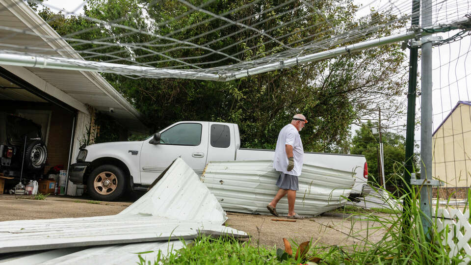 Rick Armstrong's removes metal roofing and fencing that flew from a restaurant about a block from his house and onto his truck in his driveway during Hurricane Francine on Thursday, Sept. 12, 2024 in Houma, La. (Chris Granger /The Times-Picayune/The New Orleans Advocate via AP)