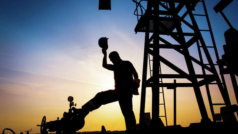 An oilfield worker silhouetted against the sky.