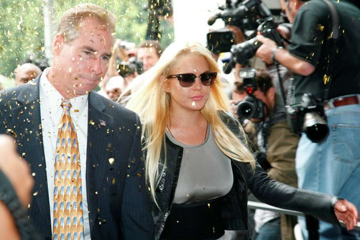 Amid a stream of confetti, actress Lindsay Lohan arrives with an official to court in Beverly Hills, Calif., Tuesday to begin her 90 day jail sentence for violating the terms of her probation.