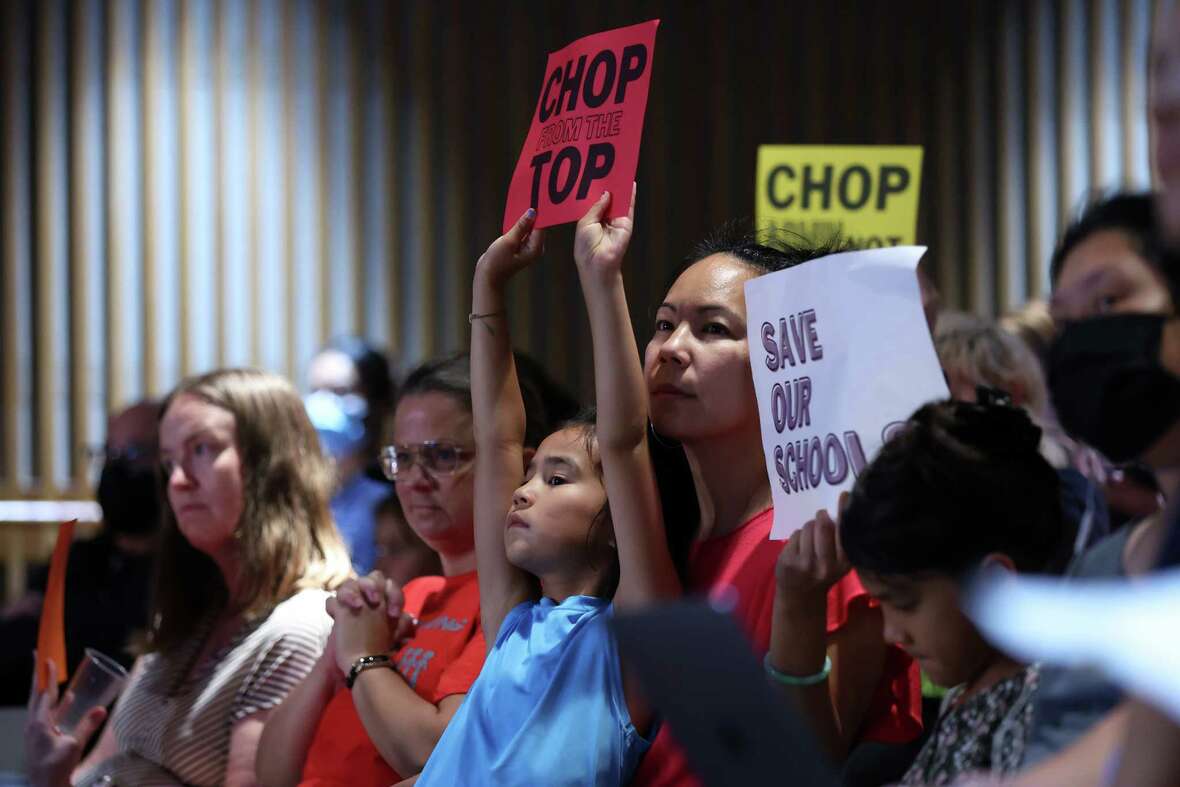 Dy Nguyen and her child, Enzo,6, hold signs during SFUSD school board meeting in San Francisco on Tuesday, August 27, 2024.