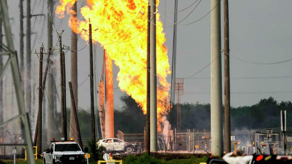 A pipeline fire burns near Spencer Highway and Summerton on Monday, Sept. 16, 2024 in La Porte. The fire caused road closures and shelter-in-place advisories Monday afternoon in the area, with evacuations to homes and businesses in the immediate area near the fire site. A damaged car is seen near the site of the fire.