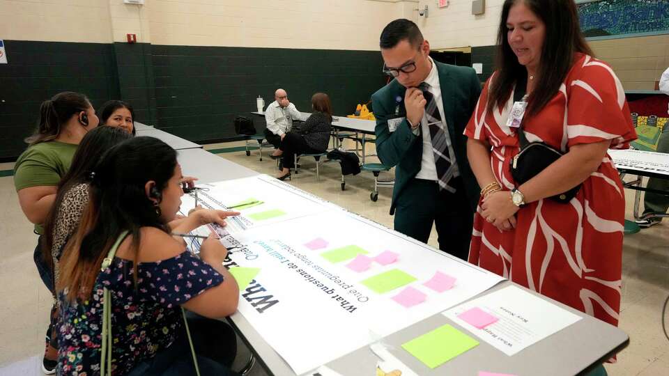 HISD’s April Coleman and Daniel Solis help parents with their questions about “what happens to…” on a giant question board at Edison Middle School on Tuesday, Sept. 17, 2024, in Houston, as HISD held a town hall for community members on the proposal in the $4.4 billion school bond to co-locate Edison Middle School and Franklin Elementary Schools.