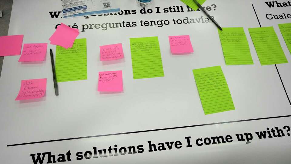 Parents with their post-it notes questions about “what happens to…” on a giant question board at Edison Middle School on Tuesday, Sept. 17, 2024, in Houston, as HISD held a town hall for community members on the proposal in the $4.4 billion school bond to co-locate Edison Middle School and Franklin Elementary Schools.