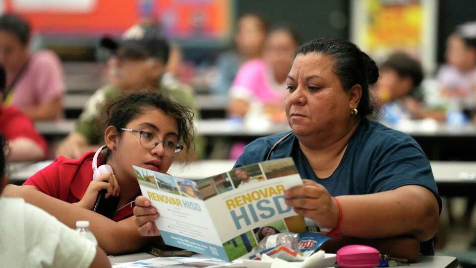 Sylvia Hernandez and her daughter Stephany, 11, look at an HISD brochure at Edison Middle School on Tuesday, Sept. 17, 2024, in Houston, as HISD held a town hall for community members on the proposal in the $4.4 billion school bond to co-locate Edison Middle School and Franklin Elementary Schools.