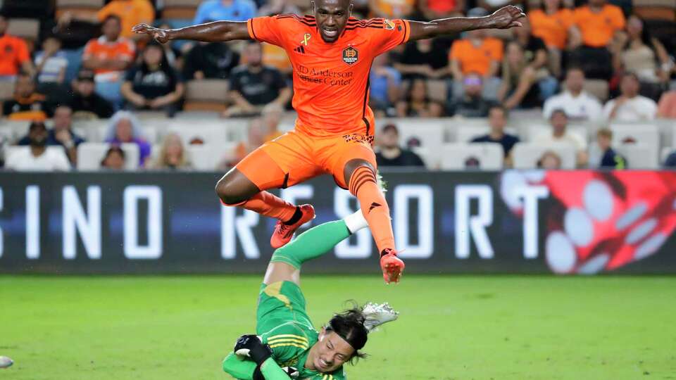 Houston Dynamo forward Ibrahim Aliyu, top, jumps over Vancouver Whitecaps goalkeeper Yohei Takaoka, bottom as Takaoka makes the save on the shot-on-goal by Aliyu during the first half of an MLS soccer match Wednesday, Sept. 18, 2024, in Houston.