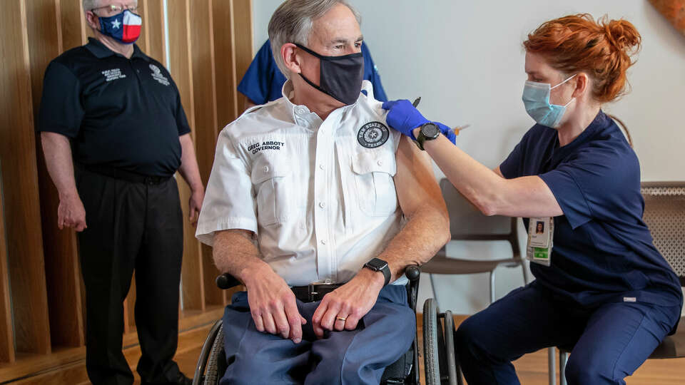 Registered nurse April Burgeons administers a dose of a Pfizer-BioNtech COVID-19 vaccine to Texas Gov. Greg Abbott at the Ascension Seton Medical Center on Tuesday, Dec. 22, 2020. Commissioner Dr. John William Hellerstedt of the Texas Department of State Health Services far left and Registered nurse Toby Hatton looks on. (Ricardo B. Brazziell /Austin American-Statesman via AP)