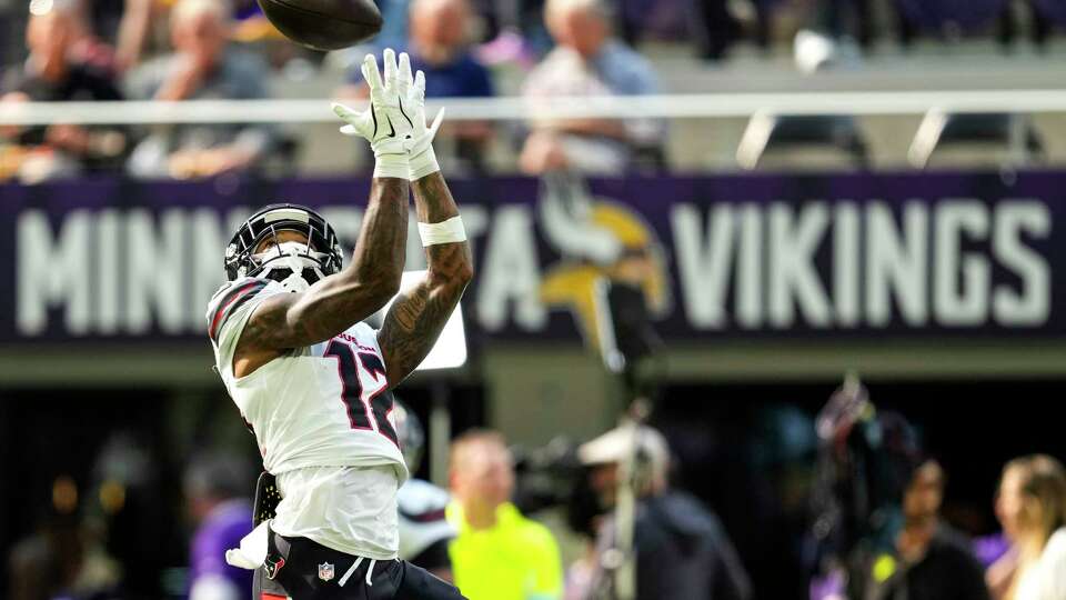 Houston Texans wide receiver Nico Collins (12) reaches up to make a catch while warming up before an NFL football game against the Minnesota Vikings Sunday, Sept. 22, 2024, in Minneapolis, Minn.