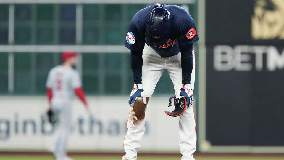 Houston Astros' Yordan Alvarez holds his right knee after sliding into second base during the third inning of an MLB baseball game at Minute Maid Park, Sunday, Sept. 22, 2024, in Houston. Alvarez left the game with trainers following the play.