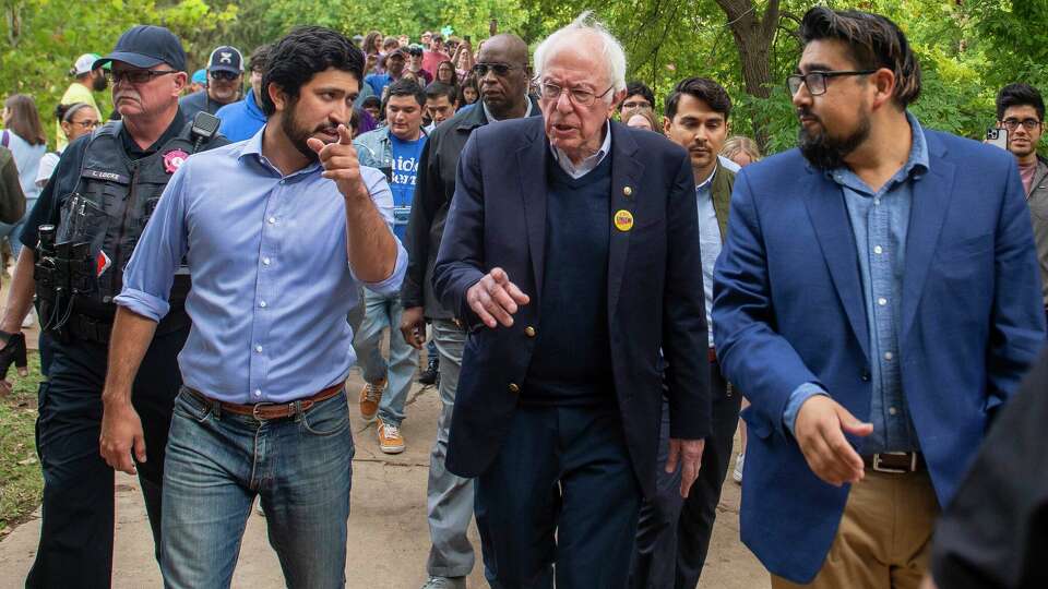 Democratic nominee for Texas Congressional District 35 , Greg Casar, left, and United States Senator Bernie Sanders (D-Vermont), center, walk to the polls followed by Texas State University during a get out the vote rally at Sewell Park in San Marcos on Sat.October, 29, 2022.