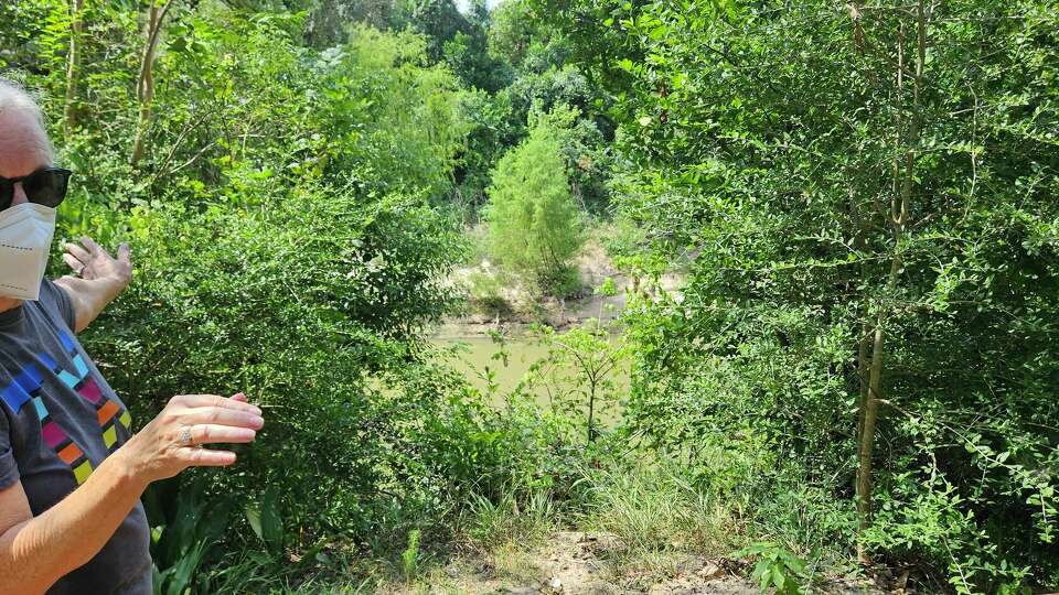 Valerie Tyler points to erosion along the Buffalo Bayou caused by previous storms, Sept. 24, 2024. 