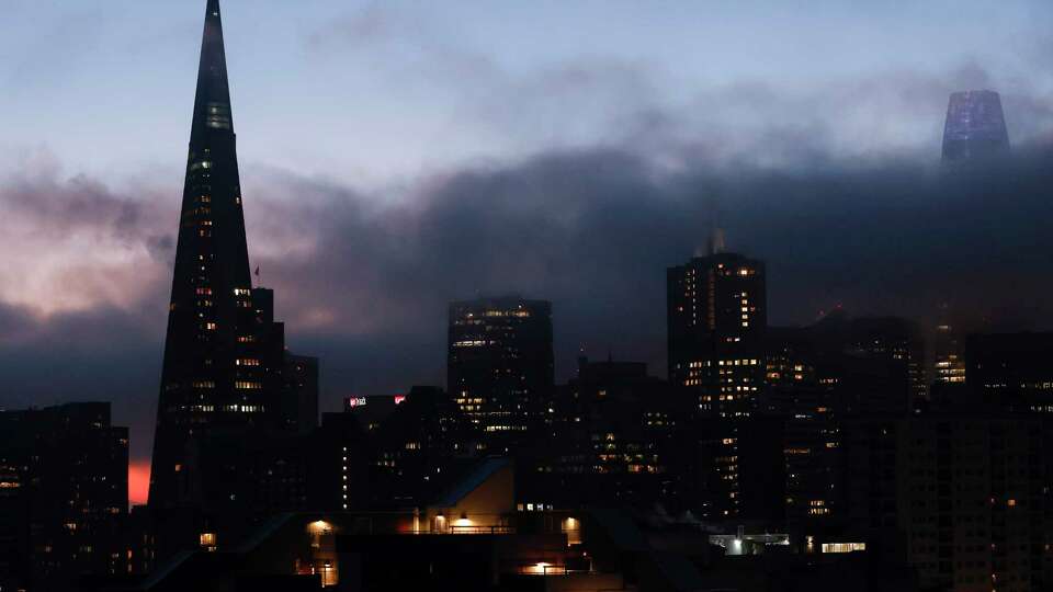 Fog creeps over as office and apartment lights are seen illuminated against the twilight sky in San Francisco, Calif. Wednesday, Dec. 7, 2022.