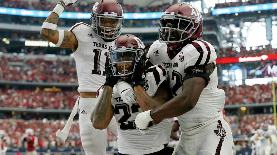 Texas A&M defensive back Larry Pryor, left, defensive back Armani Watts, center, and linebacker Otaro Alaka (42) celebrate an interception by Watts in overtime of an NCAA college football game against Arkansas, Saturday, Sept. 23, 2017, in Arlington, Texas. Texas A&M won 50-43. (AP Photo/Tony Gutierrez)