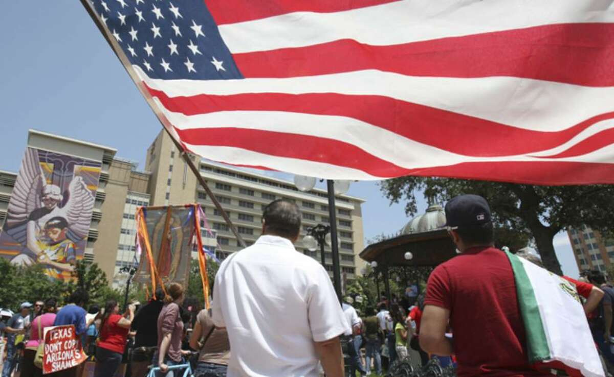 Catarino Aranda holds Old Glory while listening to the speakers in Milam Park before the march through downtown.