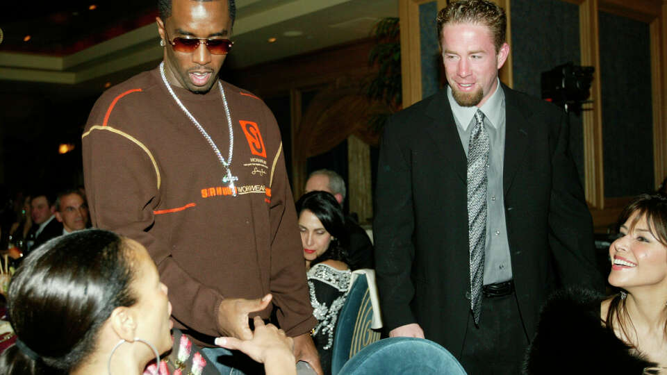 P. Diddy shakes hands with Jaci Reid as Jeff Bagwell looks on at the NFL Fashion gala held at the  Aquarium restaurant in Houston Friday Jan. 30, 2004. Bagwell's wife Ericka is seen on the far right