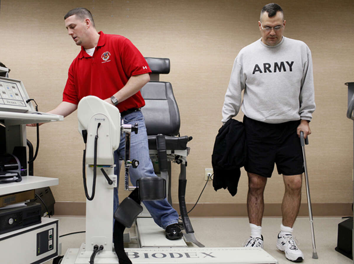 Sgt. Todd Plybon (right) works out with physical therapy assistant Mike Barber during physical therapy.