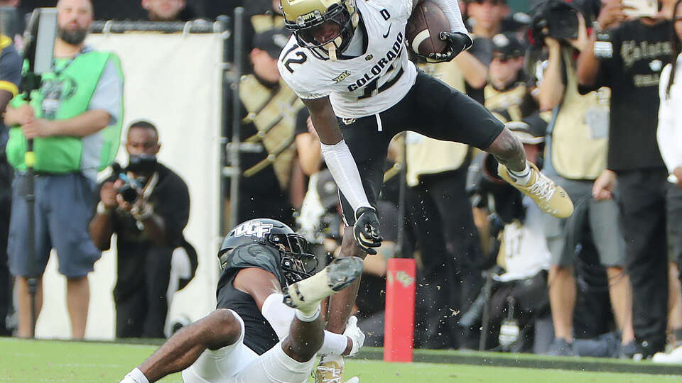 Colorado receiver Travis Hunter (12) leaps over UCF defensive back Antione Jackson.