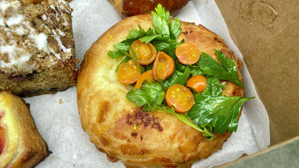 A sourdough Dutch crunch bun filled with onion bechamel and topped with sungold tomatoes and herbs from Nopa in San Francisco.