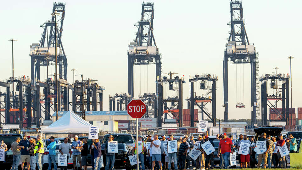 Shipping container cranes are visible in the background as Longshoremen carry signs and chant Tuesday, Oct. 1, 2024, outside the Bayport Container Terminal in Seabrook as members of the International Longshoreman’s Association have decided to strike after their contract expired at midnight. ( Kirk Sides / Houston Chronicle )