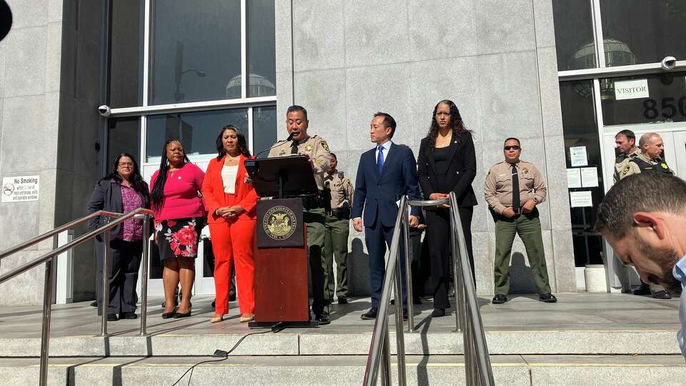 San Francisco Sheriff Paul Miyamoto, at the podium, speaks during a news conference announcing that the city will challenge a federal ruling that prevents the sheriff’s office from forcing people to consent to warrantless searching if they wish to participate in GPS monitoring. The monitoring program allows people to leave jail as they await trial. 