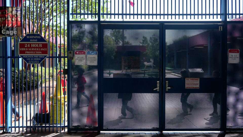 Students pass by the security gate at the entrance at Cage Elementary School, 4528 Leeland St., Wednesday, Oct. 2, 2024, in Houston. Principle Deirdre Riordan has security concerns over the open campus areas.