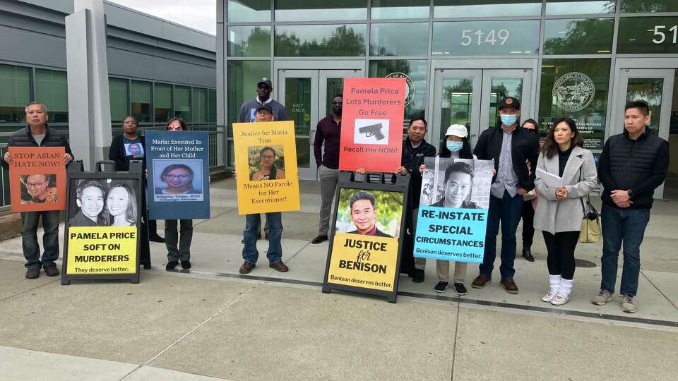 Supporters of Maria and Benison Tran hold signs with photographs of the slain couple Wednesday outside Alameda Superior?Court.