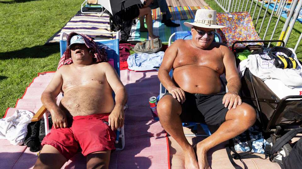 From left: David Karrigan and Mark Schliecher tan in the sun by the Banjo Stage at Hardly Strictly Bluegrass, a free music festival in Golden Gate Park in San Francisco. October 5, 2024.