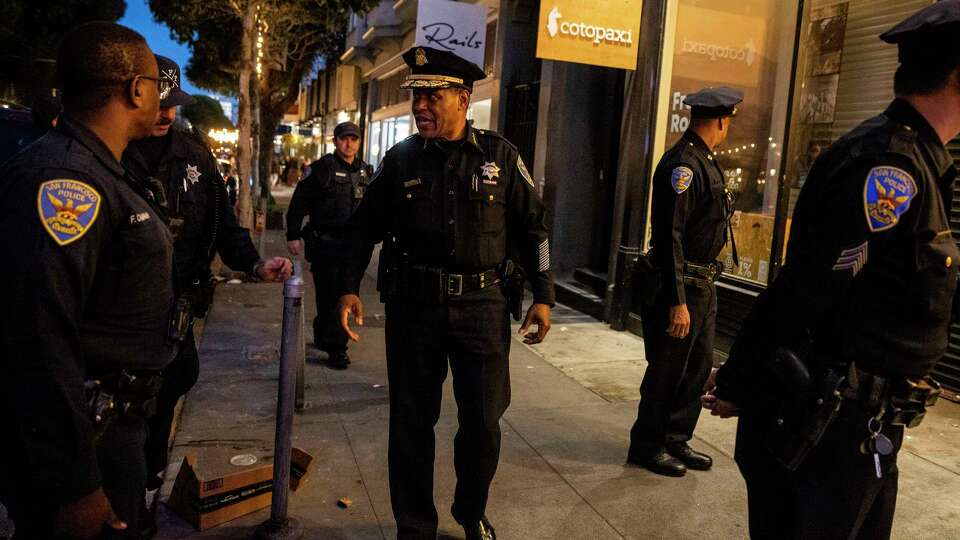 San Francisco Police Chief William Scott, center, speaks with fellow officers outside Cotopaxi during a walk days after the company CEO’s viral social media post highlighted its Hayes Valley retail store was forced to close after waves of retail theft in San Francisco, California Thursday, Oct. 27, 2022.