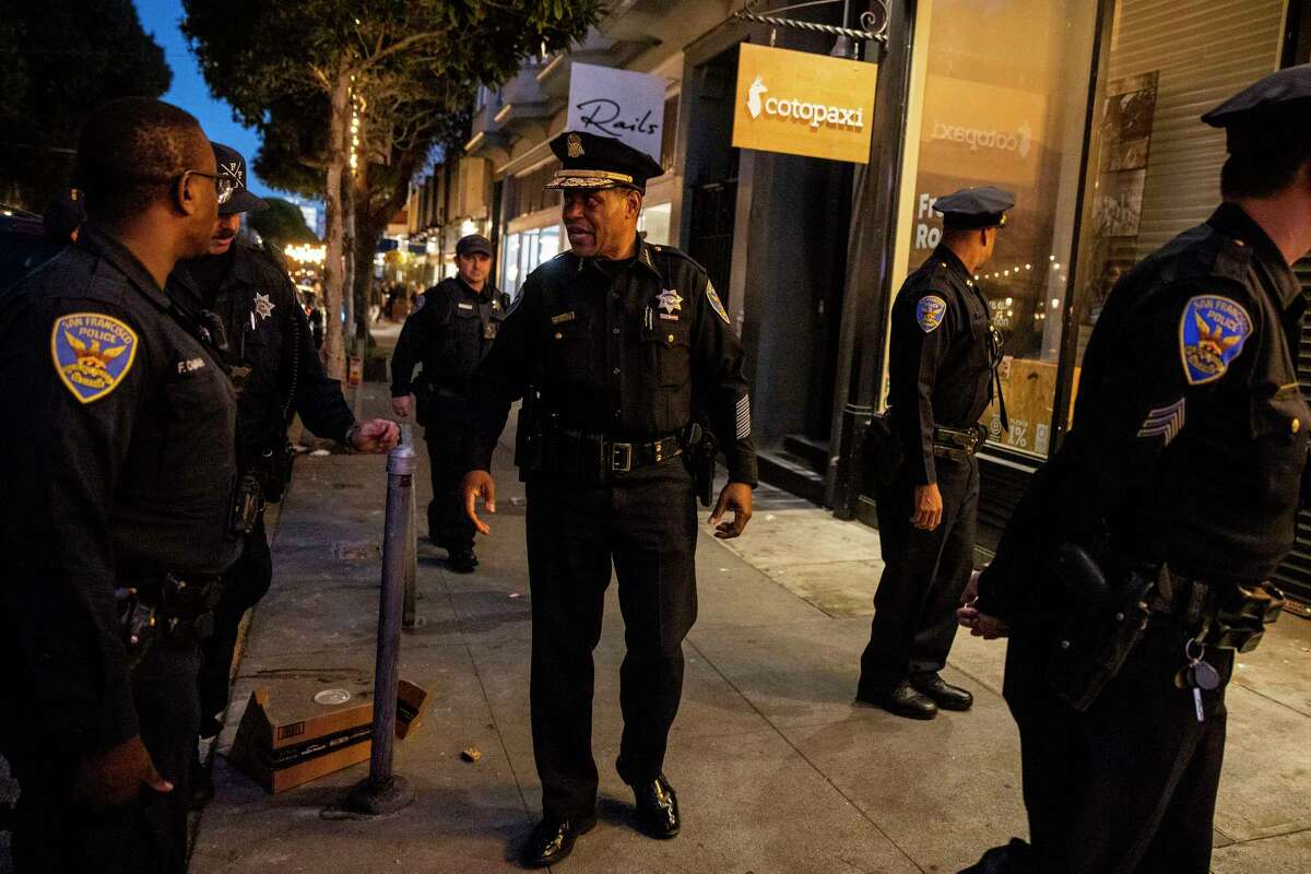 San Francisco Police Chief William Scott, center, speaks with fellow officers outside Cotopaxi during a walk days after the company CEO’s viral social media post highlighted its Hayes Valley retail store was forced to close after waves of retail theft in San Francisco, California Thursday, Oct. 27, 2022.