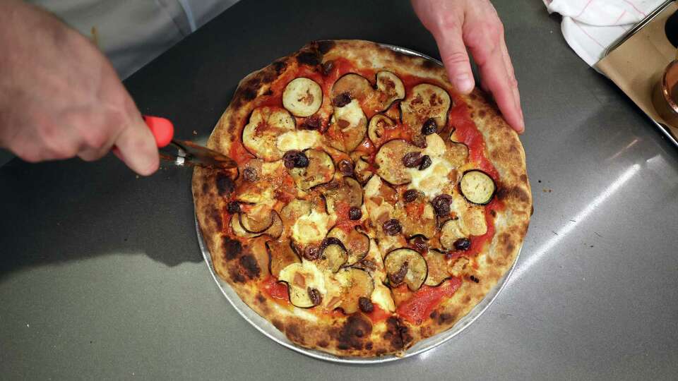 Chef Elliott Armstrong slices a pizza at Flour + Water Pizzeria in San Francisco on Monday, April 22, 2024.