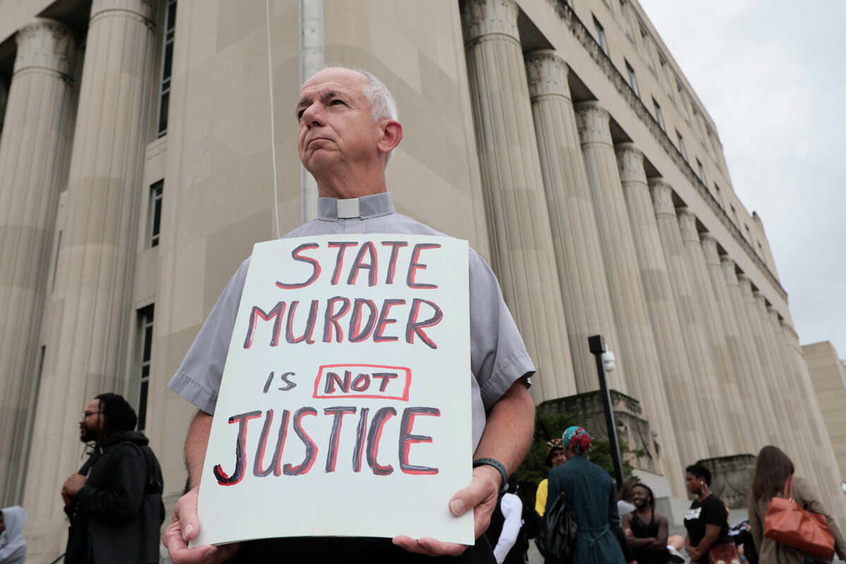 Deacon Dave Billips, with the Office of Peace and Justice with the St. Louis Archdiocese, holds a sign as he stands with protesters holding space to halt the execution of Marcellus Williams on Tuesday, Sept. 24, 2024, outside the Carnahan Courthouse in St. Louis. 