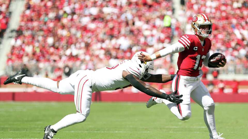 San Francisco 49ers’ Brock Purdy scrambles away from Arizona Cardinals’ Krys Barnes in 1st quarter during NFL game at Levi’s Stadium in Santa Clara, Calif., on Sunday, October 6, 2024.