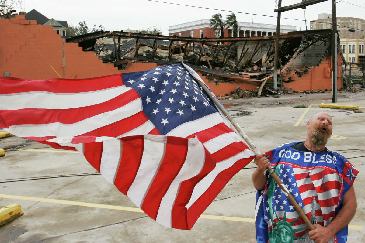 GALVESTON, TX - SEPTEMBER 24: Galveston resident Robert Shumake celebrates his gratefulness of being spared significant damage while standing in front of the remains of an art studio on Post Office Street in the Historical District September 24, 2005 in Galveston, Texas. A victorian home burned when the transformer exploded and the fire spread to a neighboring art studio. (Photo by Dave Einsel/Getty Images)