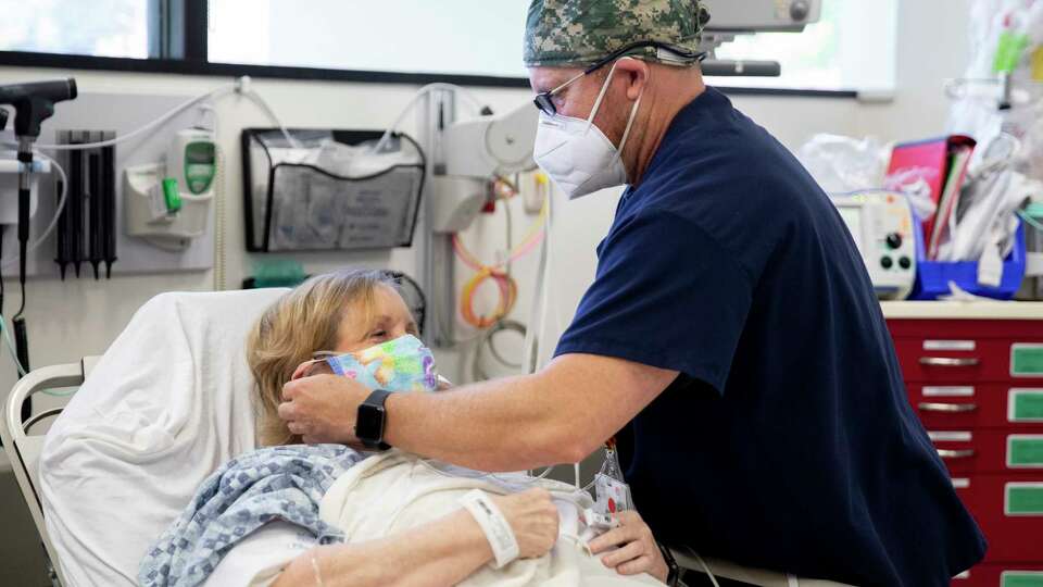 Nurse DJ (no last name given) wears a mask while checking in on a masked Los Gatos woman who declined to share her name who was admitted to the Emergency Department at Good Samaritan Hospital in San Jose, Calif. Friday, July 31, 2020 where doctors are currently treating twelve COVID-19 patients in various states of severity.