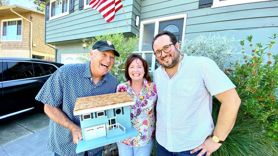 Bob and Charlene Rouspil stand with Chronicle designer Steven Boyle and the birdhouse he designed to look like their South San Francisco home.