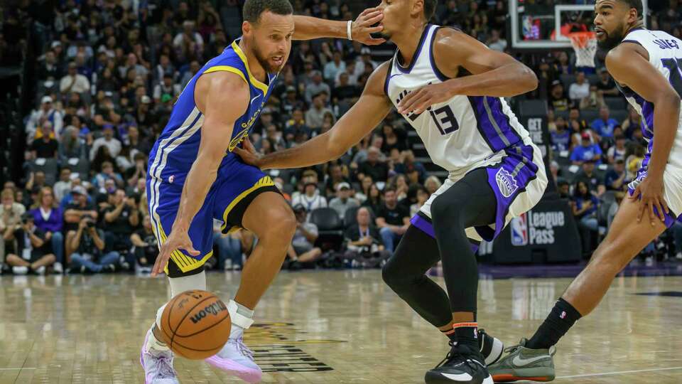 Golden State Warriors guard Stephen Curry, left, dribbles past Sacramento Kings forward Keegan Murray (13) during the first half of a preseason NBA basketball game in Sacramento, Calif., Wednesday, Oct. 9, 2024. (AP Photo/Randall Benton)