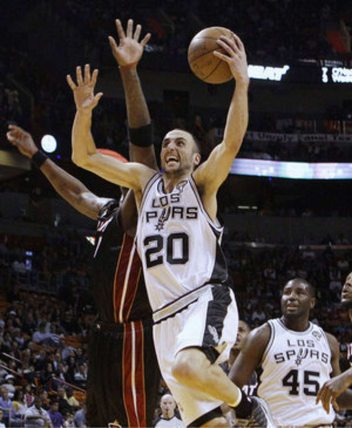 The Spurs' Manu Ginobili goes to the basket against the Heat's Jermaine O'Neal (left) as teammate DeJuan Blair (45) watches.