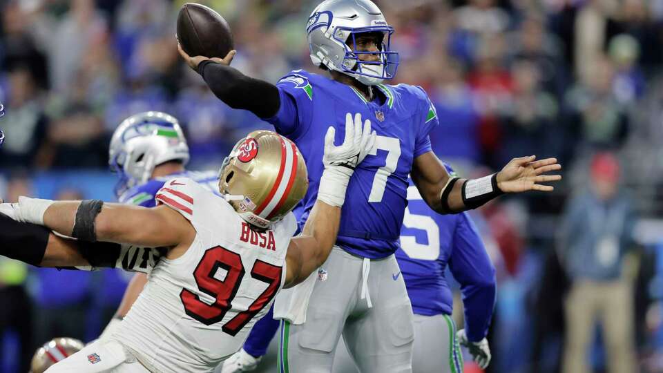 Seattle Seahawks quarterback Geno Smith (7) passes under pressure from San Francisco 49ers defensive end Nick Bosa (97) during the first half of an NFL football game, Thursday, Oct. 10, 2024, in Seattle. (AP Photo/John Froschauer)