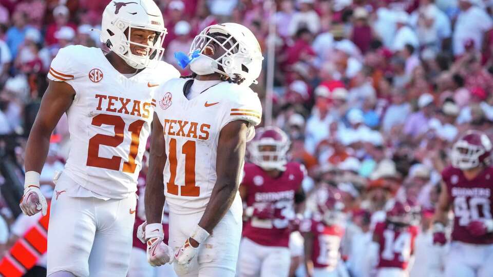 Texas Longhorns defensive back Xavier Filsaime (21) and linebacker Colin Simmons (11) celebrate after tackling Oklahoma Sooners quarterback Michael Hawkins Jr. during the fourth quarter of an NCAA college football game between Texas and Oklahoma at the Cotton Bowl, Saturday, Oct. 12, 2024, in Dallas.