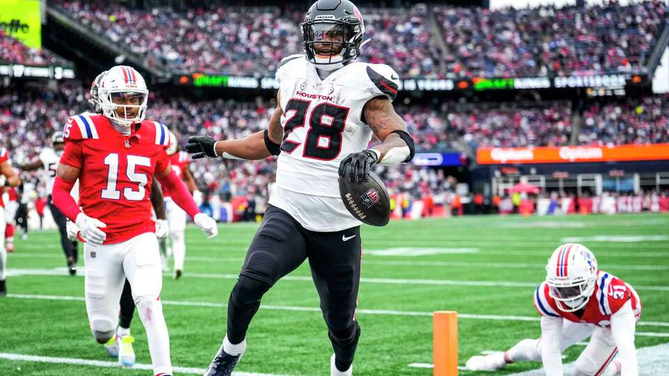 Houston Texans running back Joe Mixon (28) runs across the goal line past New England Patriots safety Marte Mapu (15) and cornerback Jonathan Jones (31) on a 20-yard touchdown run during the second half of an NFL football game Sunday, Oct. 13, 2024, in Foxborough, Mass.