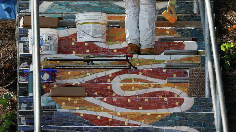 A worker with KZ Tile Company works over tiles with sparkles as he works at the Burnside staircase on Tuesday, October 15, 2024 in San Francisco, Calif.