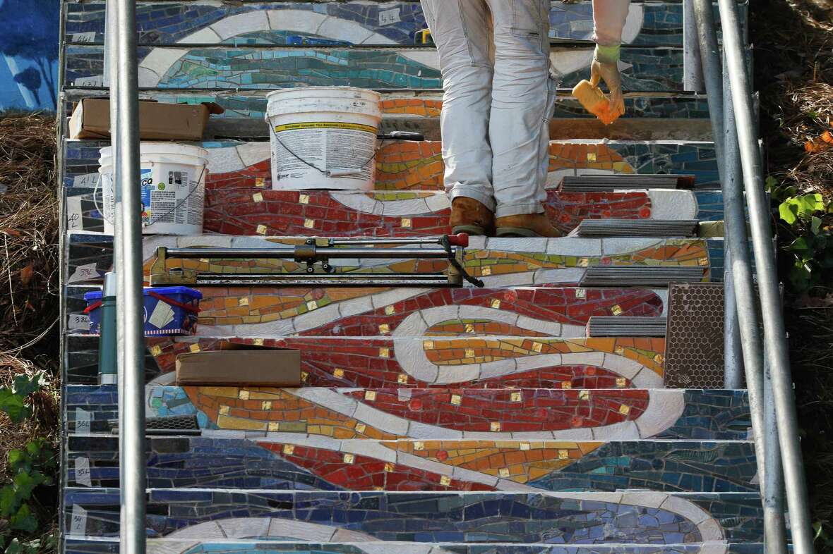 A worker with KZ Tile Company works over tiles with sparkles as he works at the Burnside staircase on Tuesday, October 15, 2024 in San Francisco, Calif.