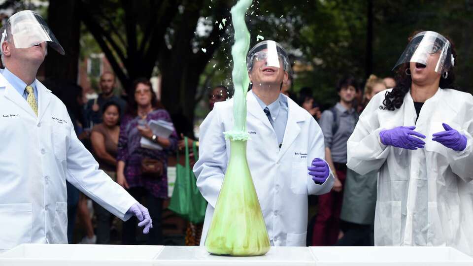 Yale University President Peter Salovey (center) watches blue foam shoot out from a beaker during a chemical reaction set up to entertain the crowd at the fifth annual Founders Day celebration on Yale University's Cross Campus in New Haven on October 9, 2018. The event also coincides with the tenth anniversary of the acquisition of the Yale's West Campus.