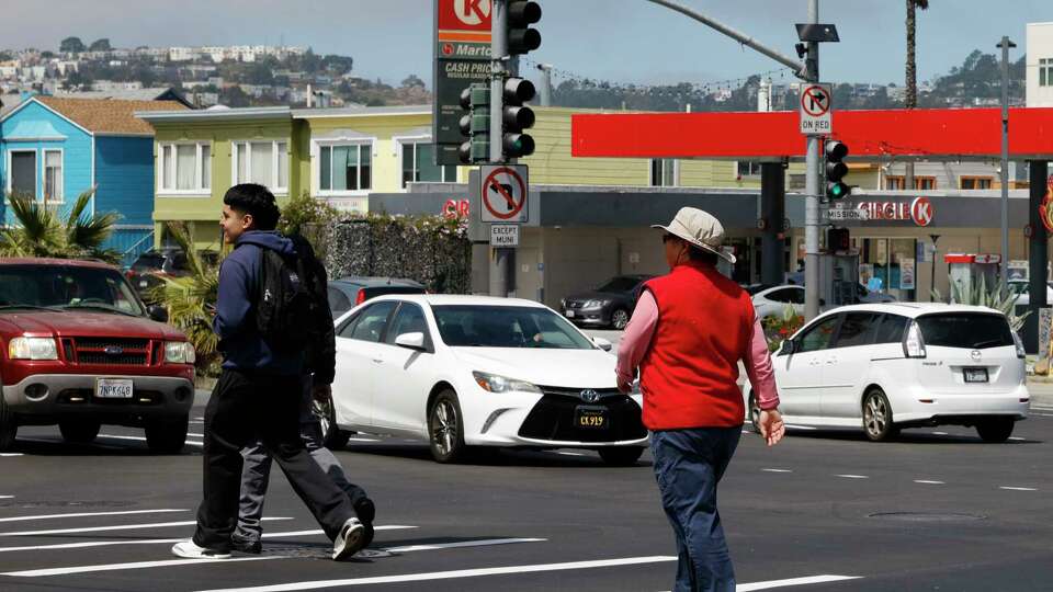 Pedestrians cross at Mission Street and Geneva Avenue in San Francisco on Wednesday, Aug. 21, 2024.