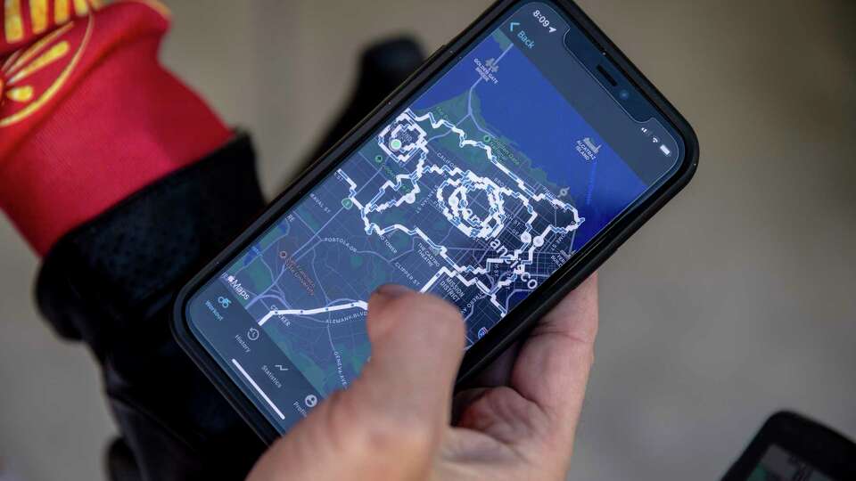 Jakub 'Kuba' Mosur checks a pre-plotted route on his phone as he prepares for a bike ride that resembles a great horned owl in the fitness tracking app Strava in San Francisco, Calif. Saturday, April 9, 2022. Mosur, a photographer and a father of two, started cycling carefully plotted routes on his fixed gear bike 'Le Vizir', named after one of Napoleon Bonaparte's horses, across the city during the pandemic as a creative outlet, and is part of a growing community of artists across the globe who create similar contour maps by cycling and running.