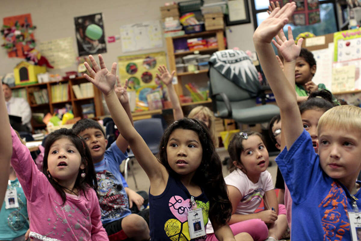 Kindergartners including Angel Meza, 5, (from left) John Contreras, 6, Giselle Barrios, 6, Madison Monita, 6, and Travis Barker, 6, raise their hands to answer a question in Cathleen Henry's kindergarten class at Northern Hills Elementary School in San Antonio on May 14.