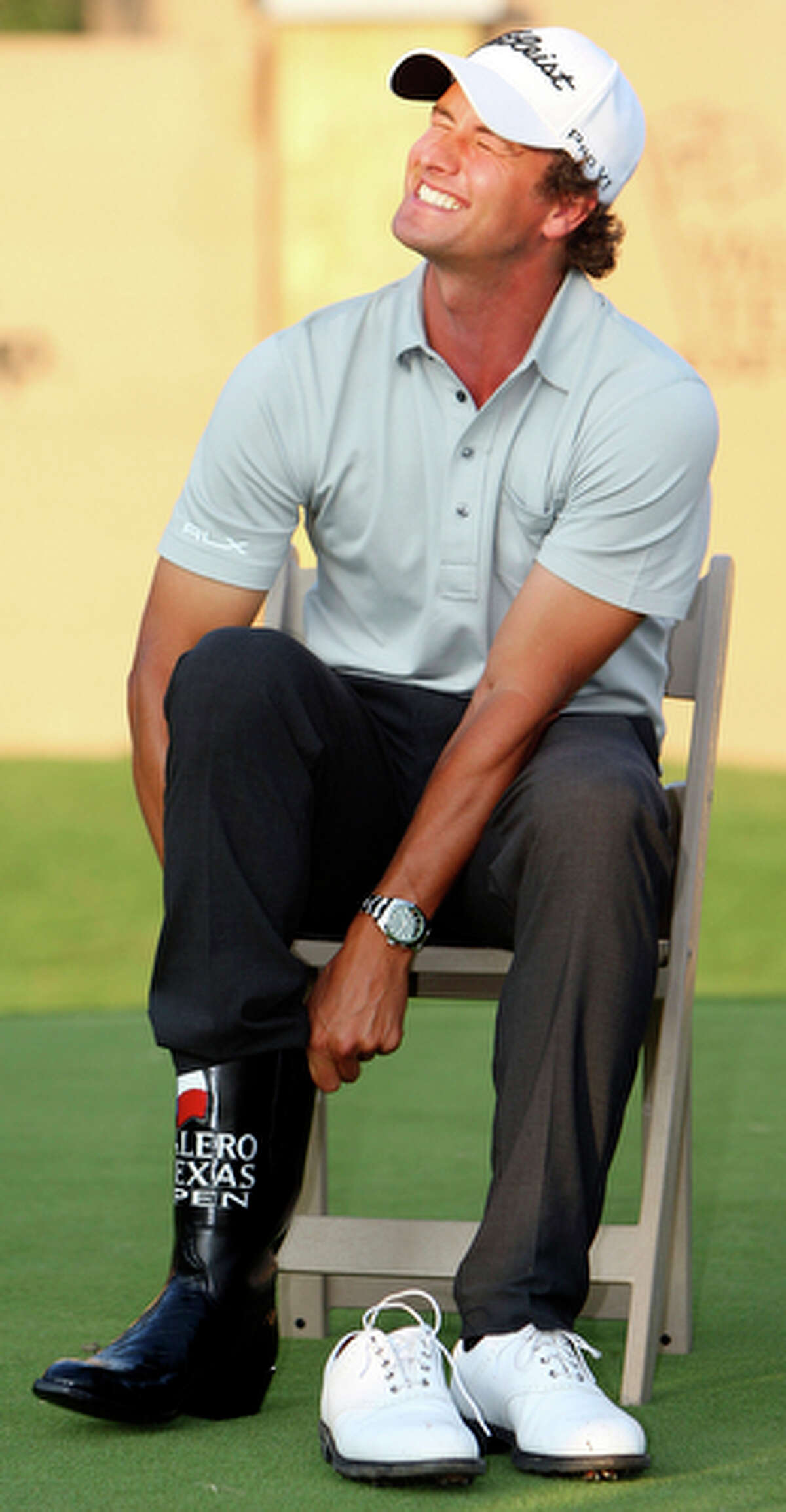 Adam Scott struggles to put on a pair of boots after winning the Valero Texas Open.
